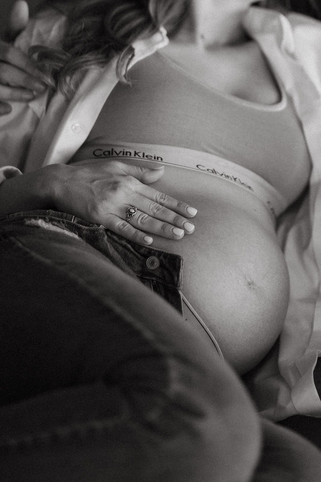 Black and white closeup of a pregnant belly in Calvin Klein activewear.