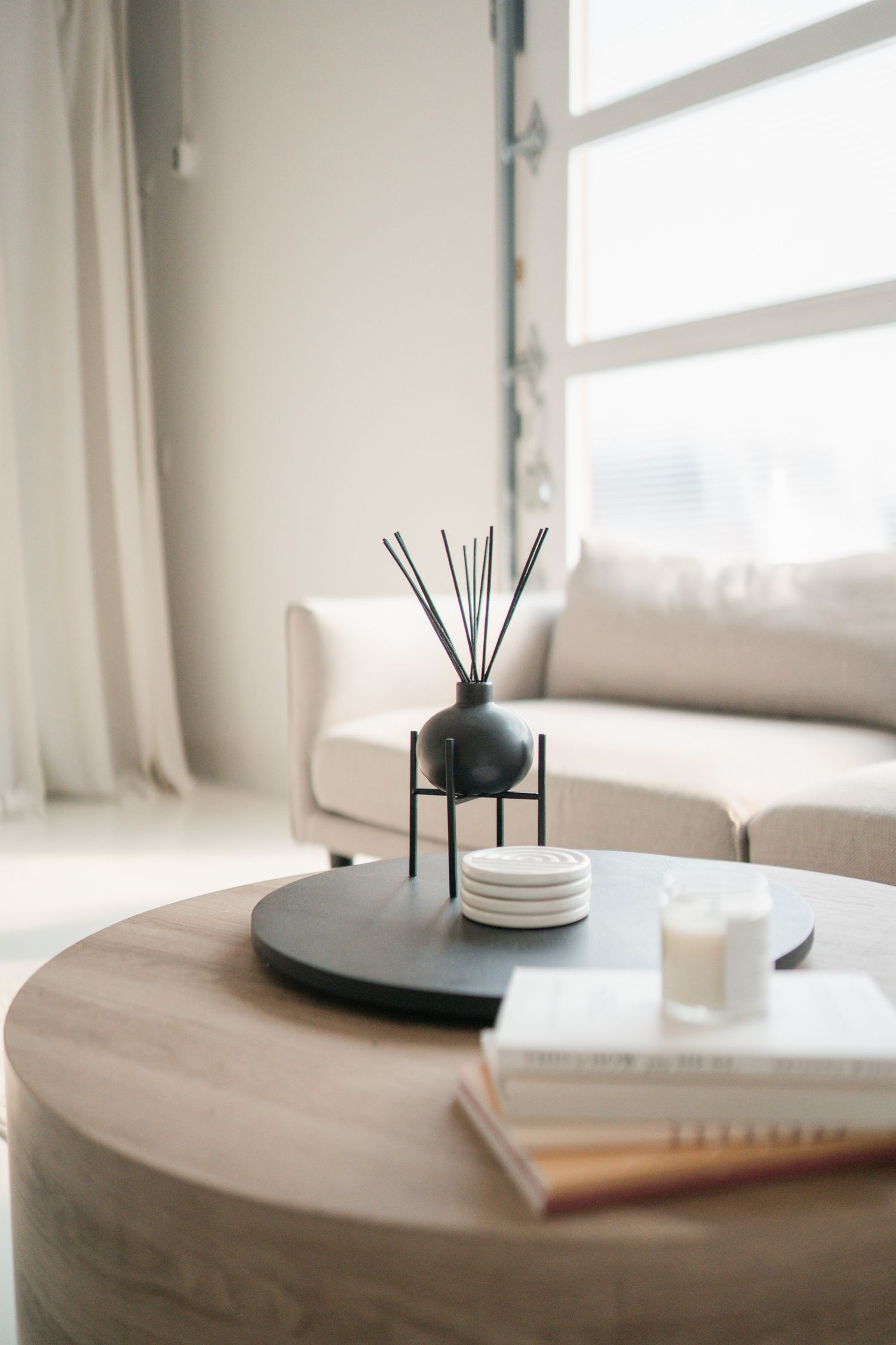 Five minimalist lifestyle scenes showing reed diffusers, white plates, and notebooks on light wooden surfaces in bright rooms.