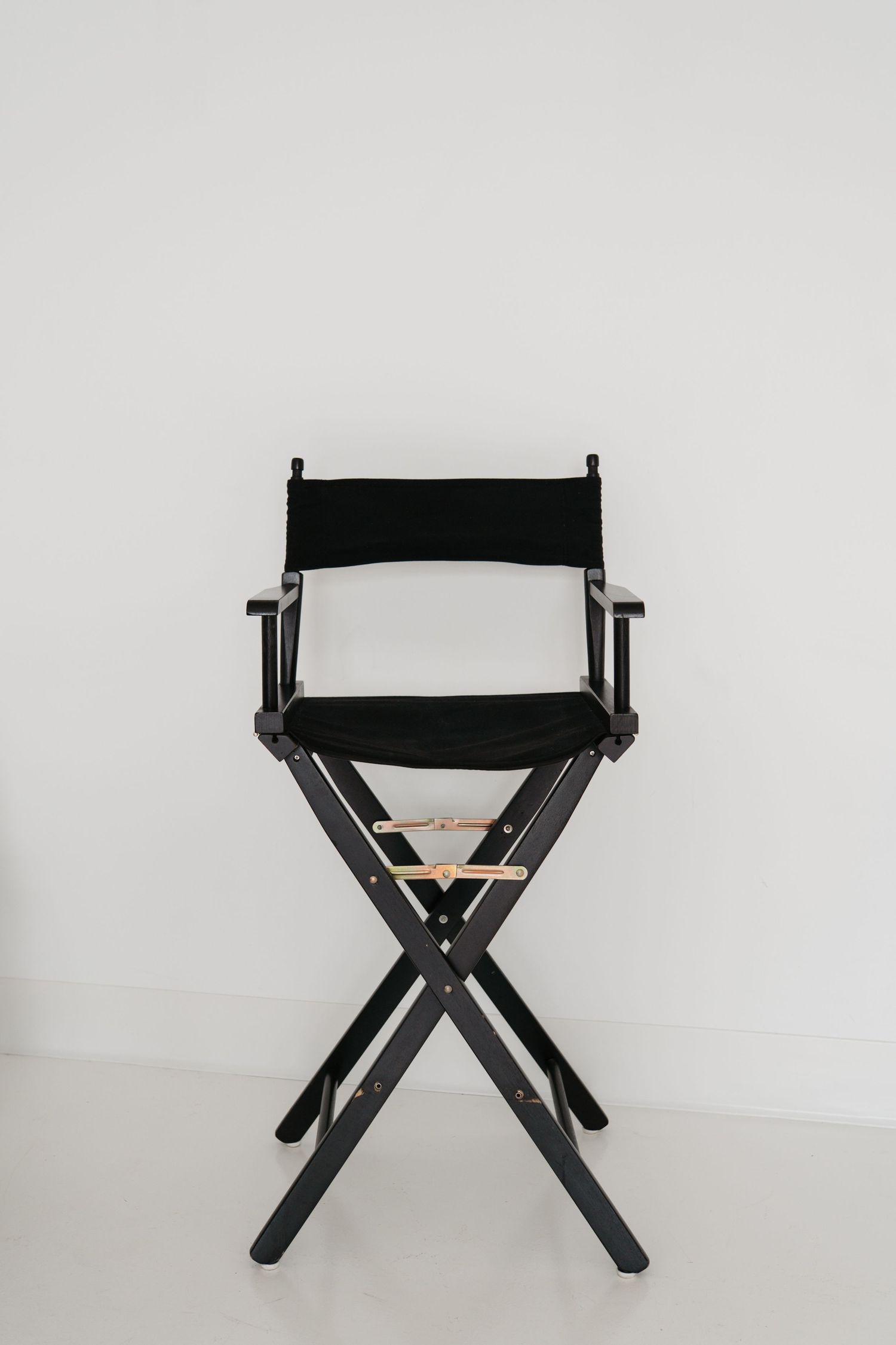 Black director's style folding chair shown from different angles on white background.