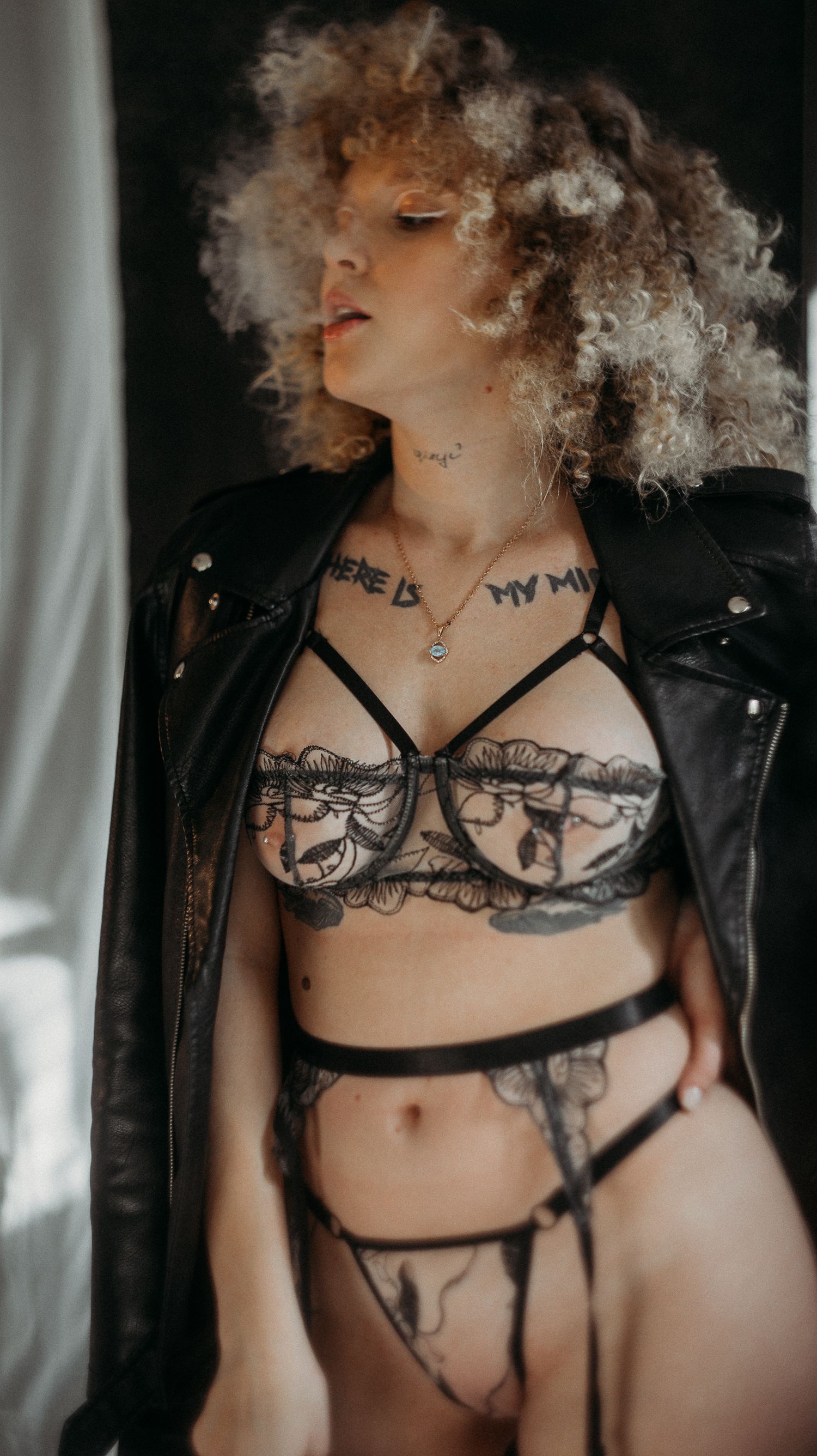Artistic boudoir portrait featuring black lace lingerie and leather jacket.