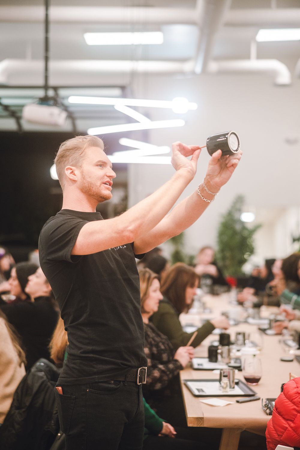 A bartender in black demonstrates cocktail techniques during a tasting event.