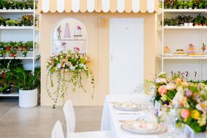 An elegant event space decorated with pastel floral arrangements and white chairs.