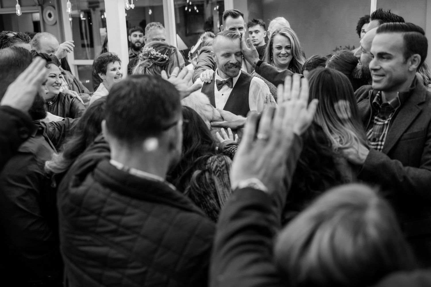 An energetic crowd at an event raises hands in unison during a black and white photo moment.