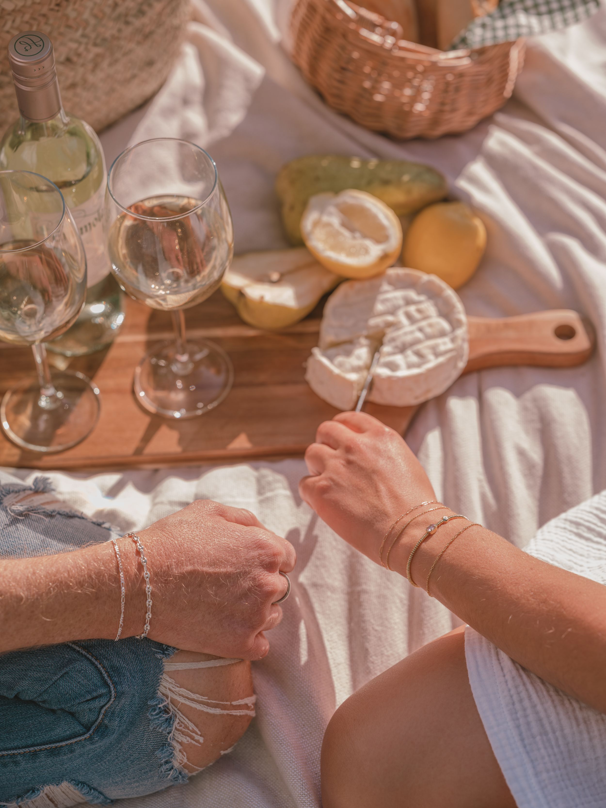 Wine glasses and citrus fruits arranged on a wooden board for an outdoor picnic.