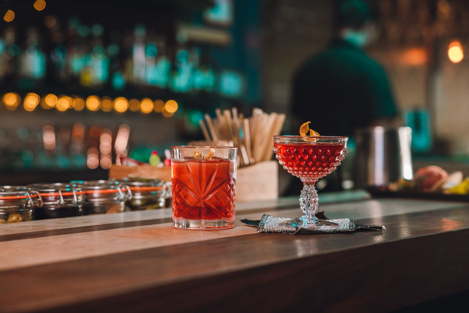 Colorful cocktails displayed on a dark bar counter with elegant glassware and garnishes.