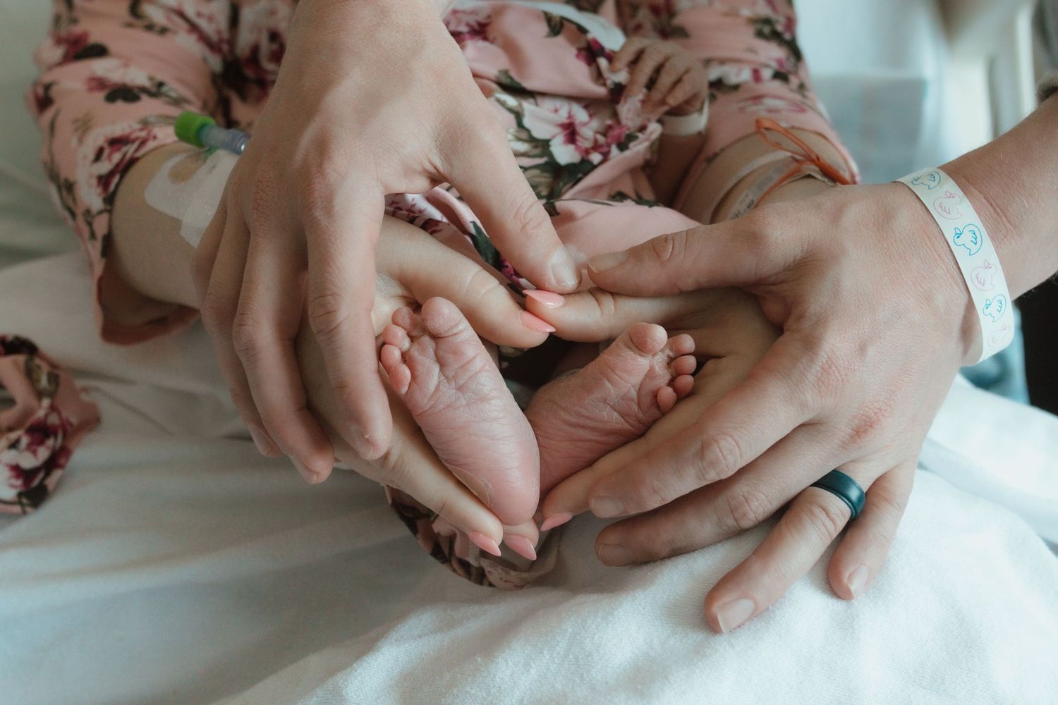 Close-up of sleeping baby's hand resting on white bedding.