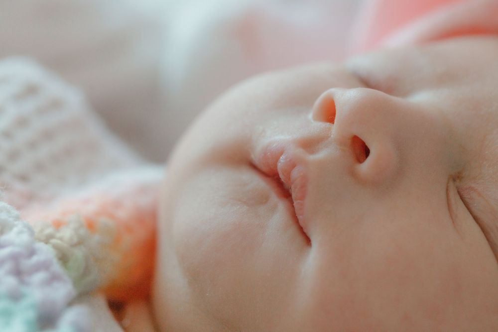 Close-up view of sleeping baby with delicate features in soft lighting.
