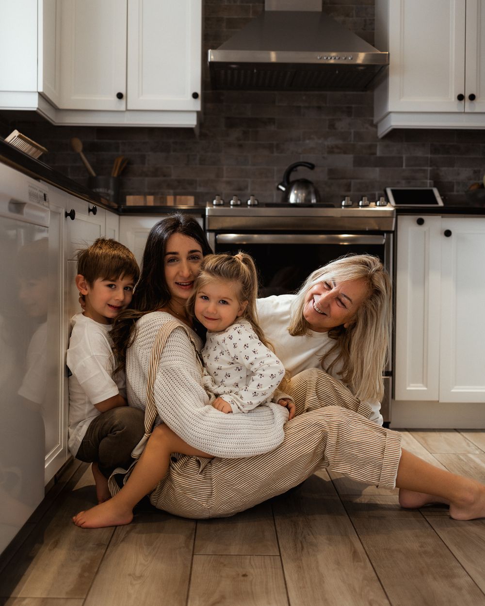 Casual family group sitting together on kitchen floor.