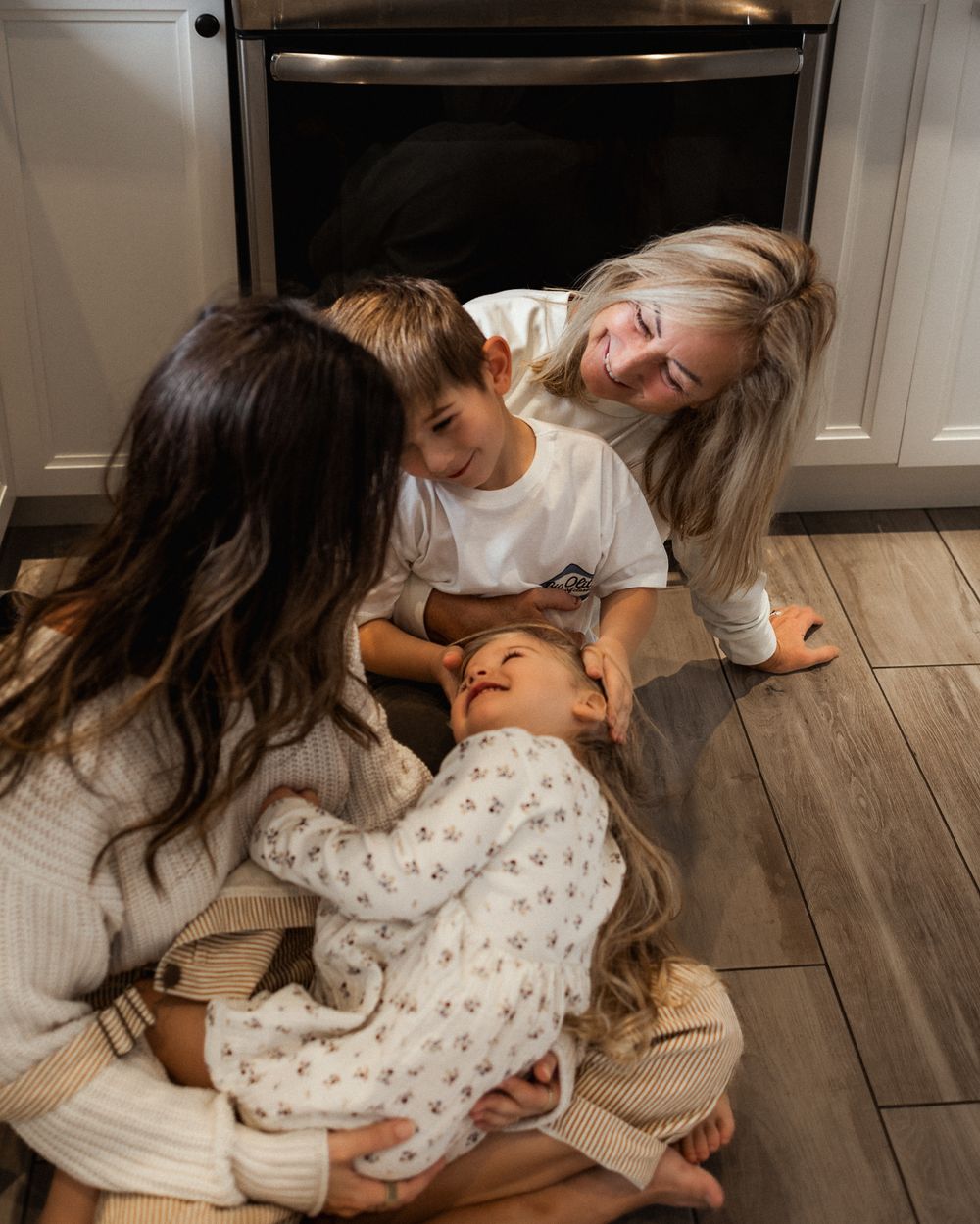 Family sharing playful moment together on kitchen floor.
