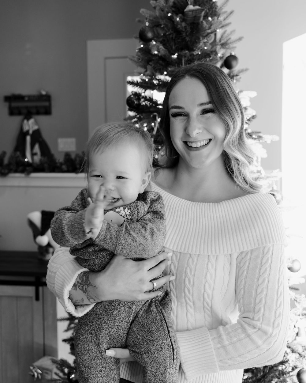 Black and white photos capture tender holiday moments by a decorated Christmas tree.