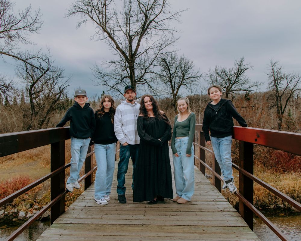 A wooden boardwalk surrounded by autumn foliage with people gathered for a photo.