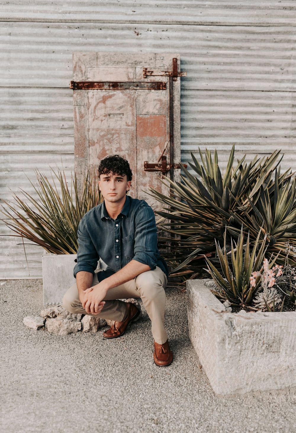 senior boy poses in front of rustic barn at the flour mill in mckinney