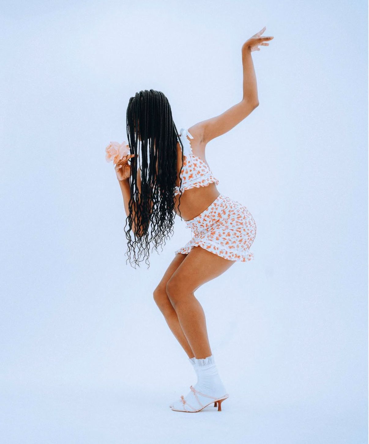 Dance-inspired fashion shoot with flowing white dress against minimal blue background.