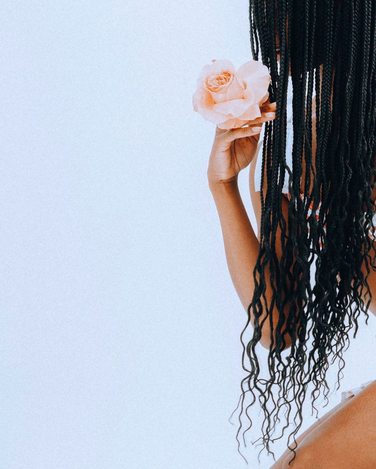 Dramatic hair movement captured against a minimalist white backdrop with peachy floral details.