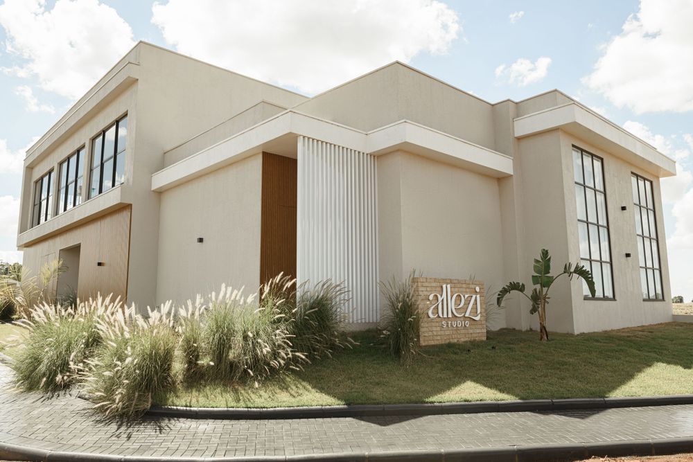 Modern beige building exterior with decorative grasses and large windows.