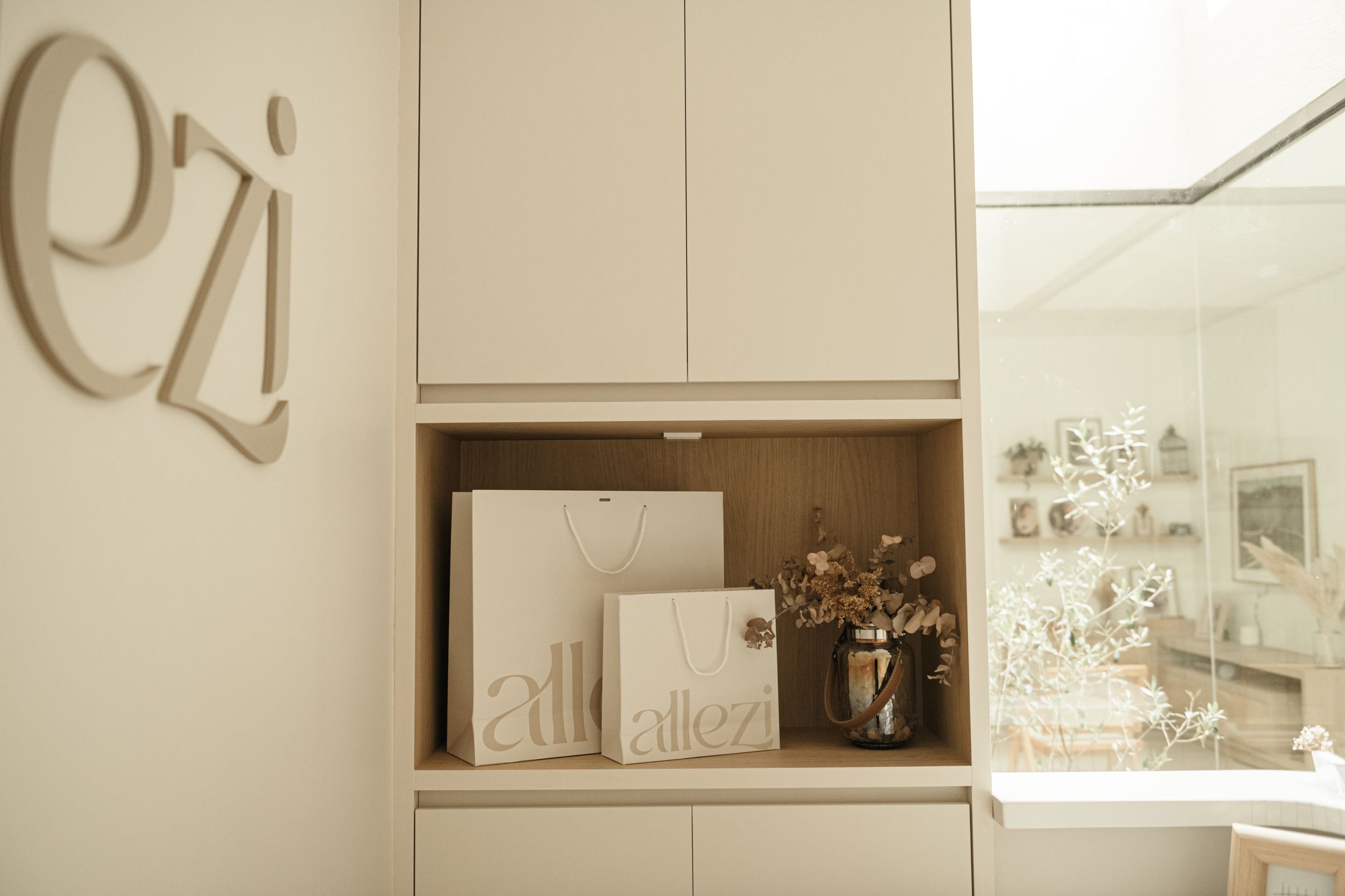 Built-in storage cabinet displaying studio branding materials in neutral tones.