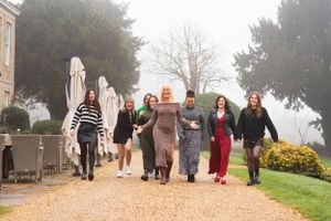 A group of friends walk together and hold hands on a foggy autumn day at an outdoor venue.