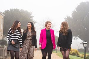 Four friends enjoy a stroll together on a foggy day, one wearing a vibrant pink blazer.