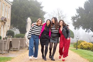 Group of friends walking arm in arm outdoors wearing colorful casual outfits on a foggy day.
