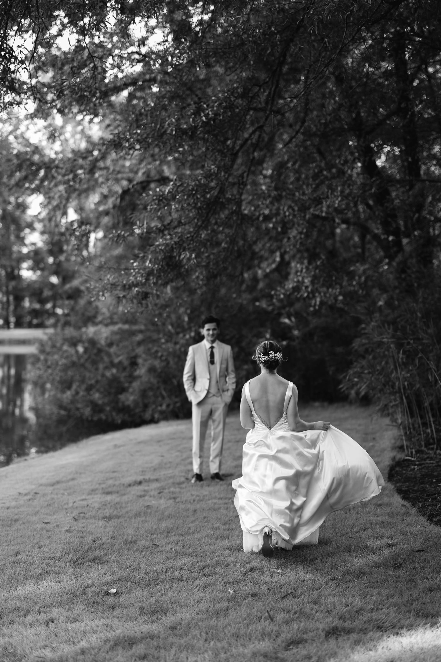 A black and white sequence showing a couple rolling down a grassy hill in wedding attire.