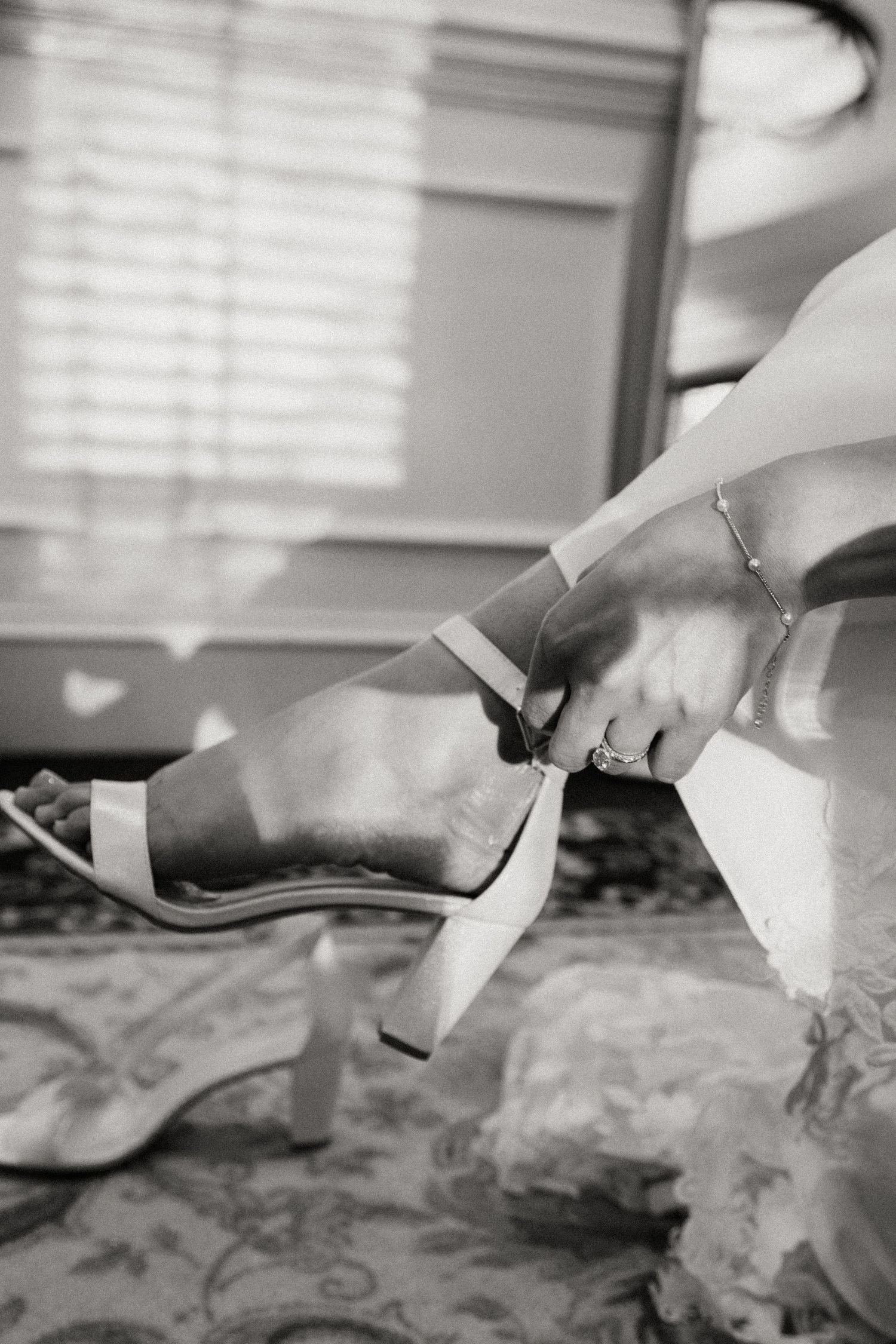 Close-up of white bridal shoes being put on against patterned fabric.