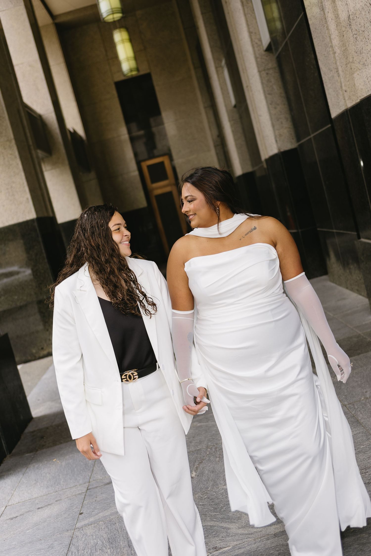 A group wearing all white outfits walks together along a covered walkway.