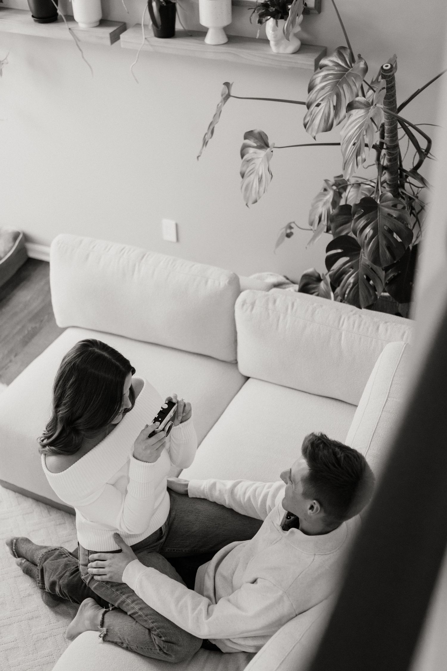 Black and white photo of couple relaxing on white couch in modern living room.