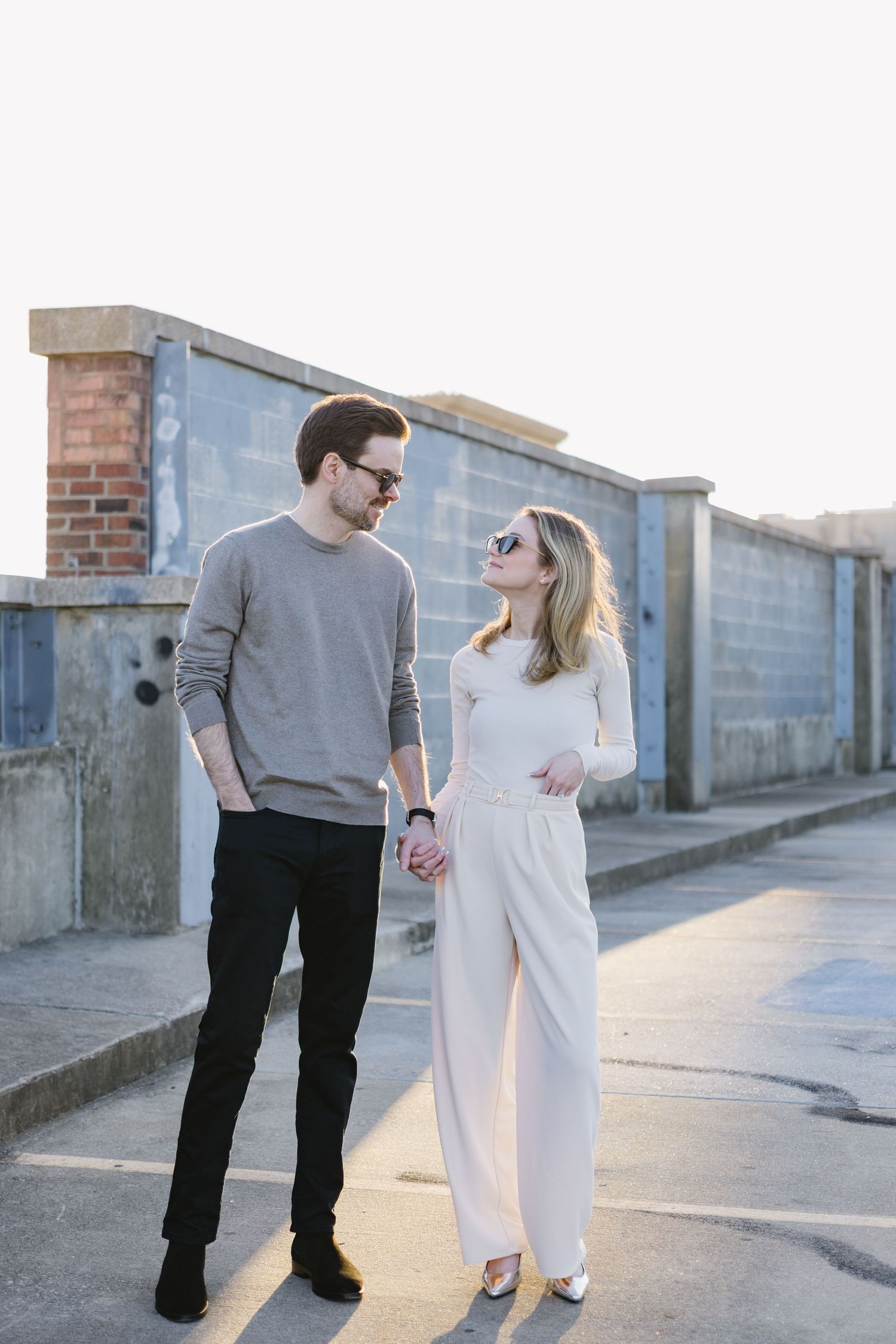 Casual couple walking and laughing together on an urban pathway at sunset.