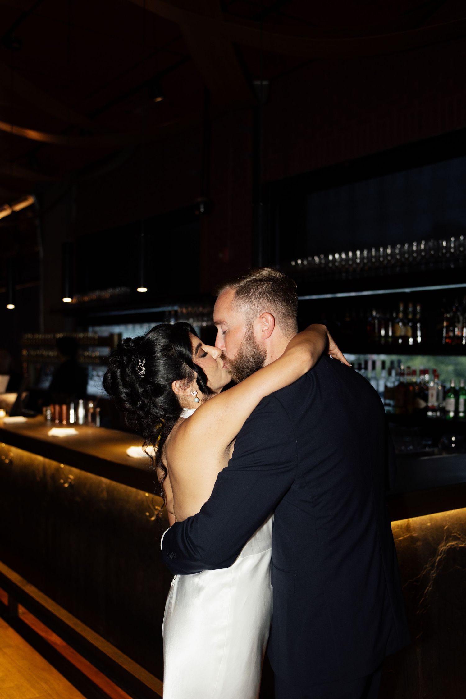 A romantic couple shares an intimate moment in a dimly lit setting.