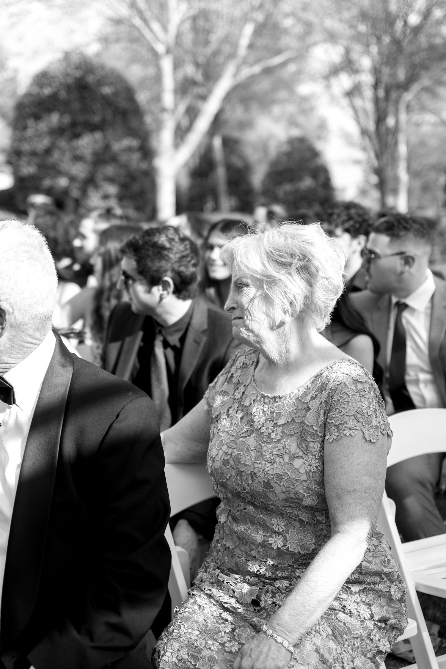 Wedding guests seated at an outdoor ceremony in black and white.