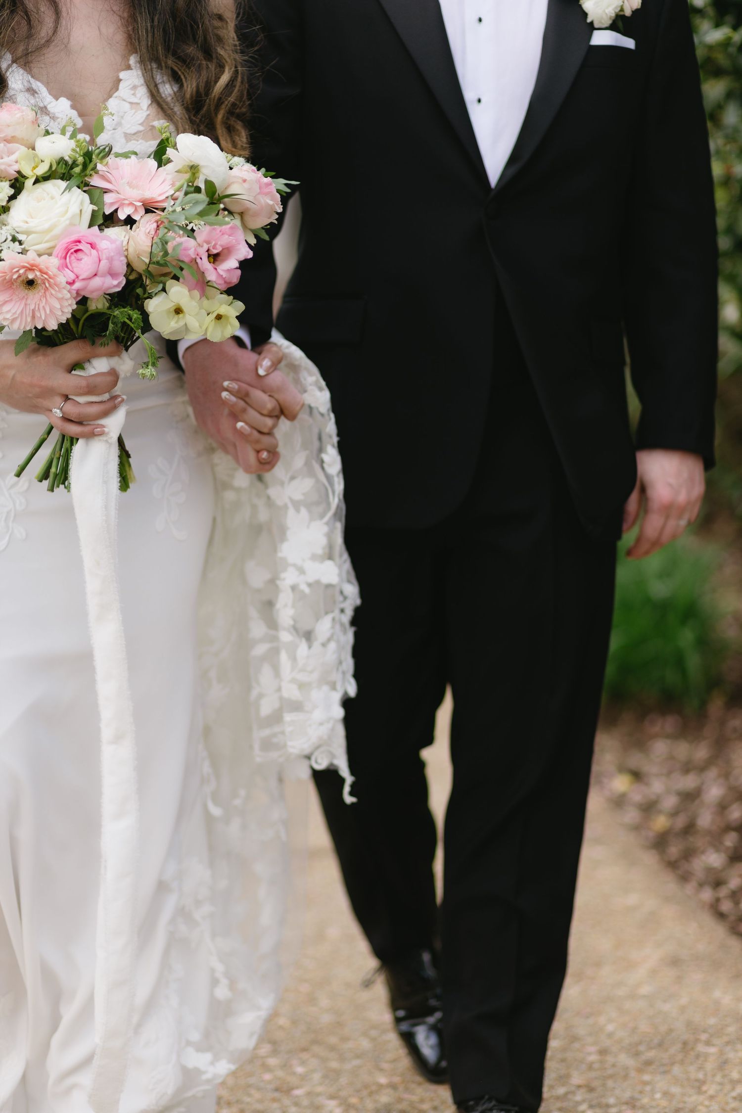 Wedding couple in formal attire holding pink and white floral bouquets.