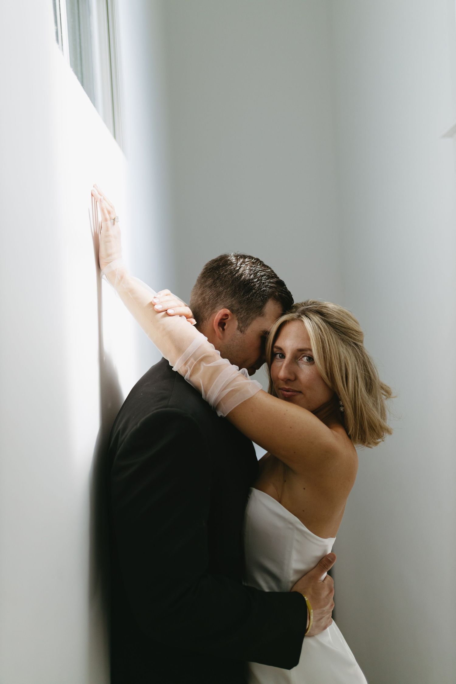 Artistic black and white photography sequence capturing intimate moments between a couple near a wall.