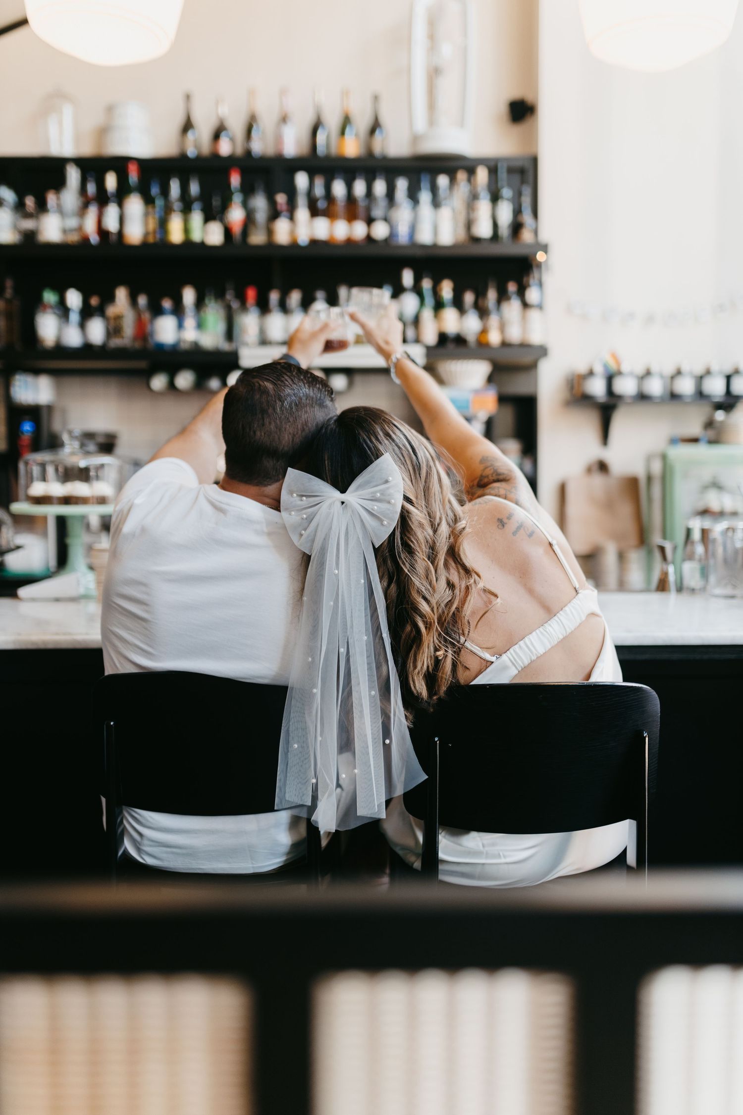 Couple sitting at bar counter with bridal veil visible.