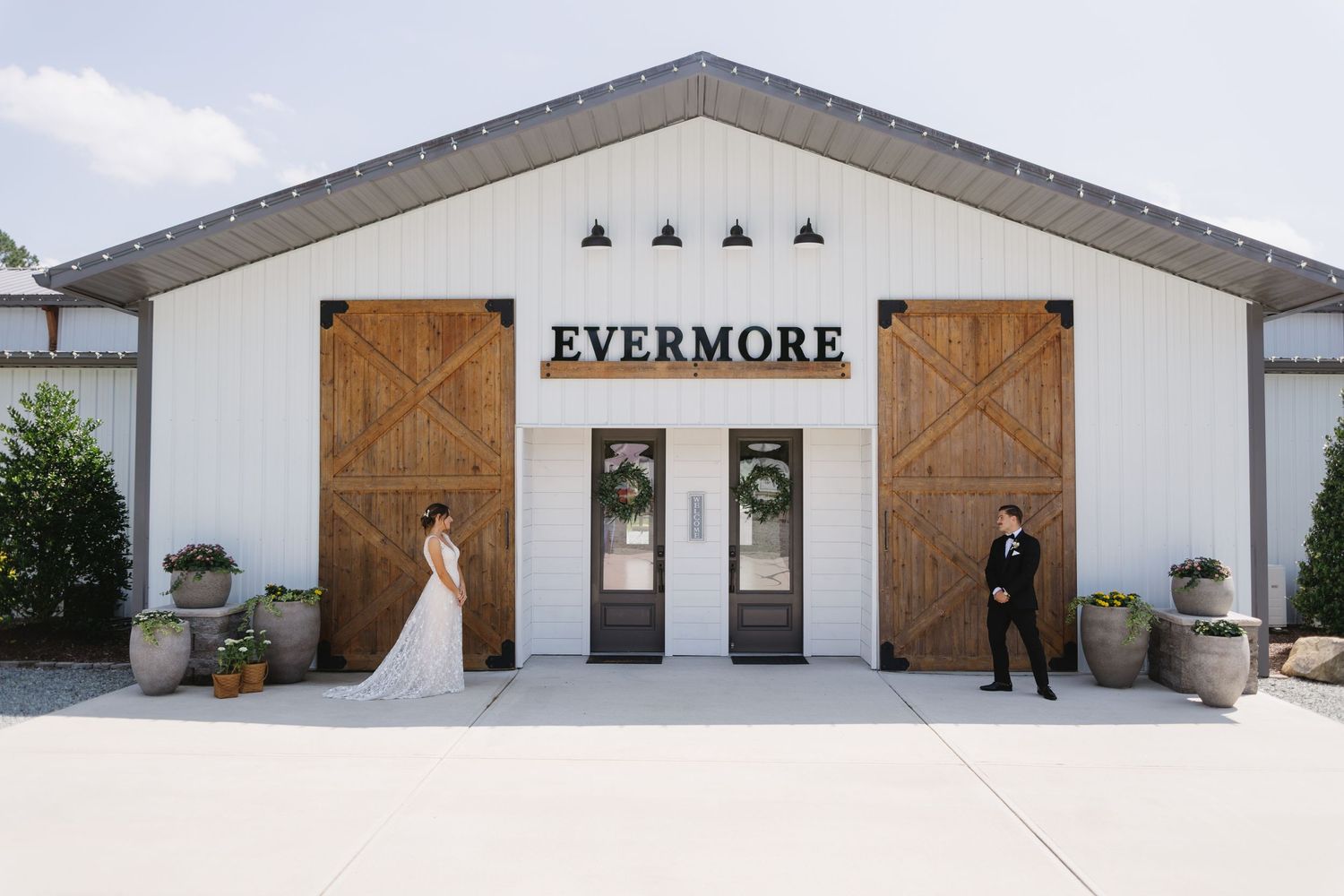 A couple poses for wedding photos outside the rustic Evermore venue entrance.