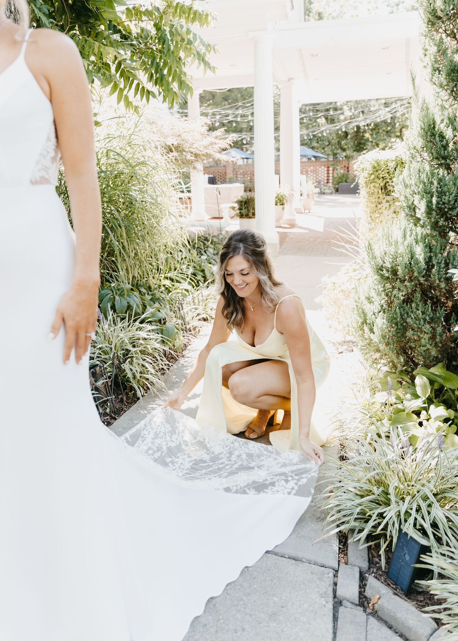 Wedding dress being adjusted in a garden setting.
