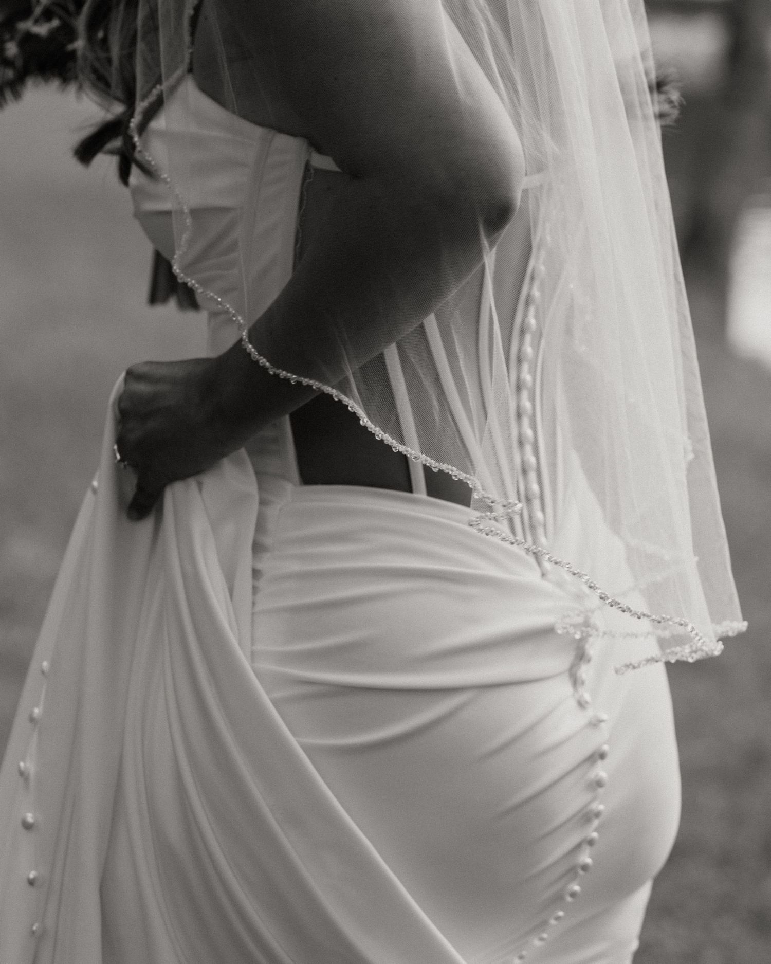 Detail shot of a wedding dress showing intricate button closures and flowing fabric.