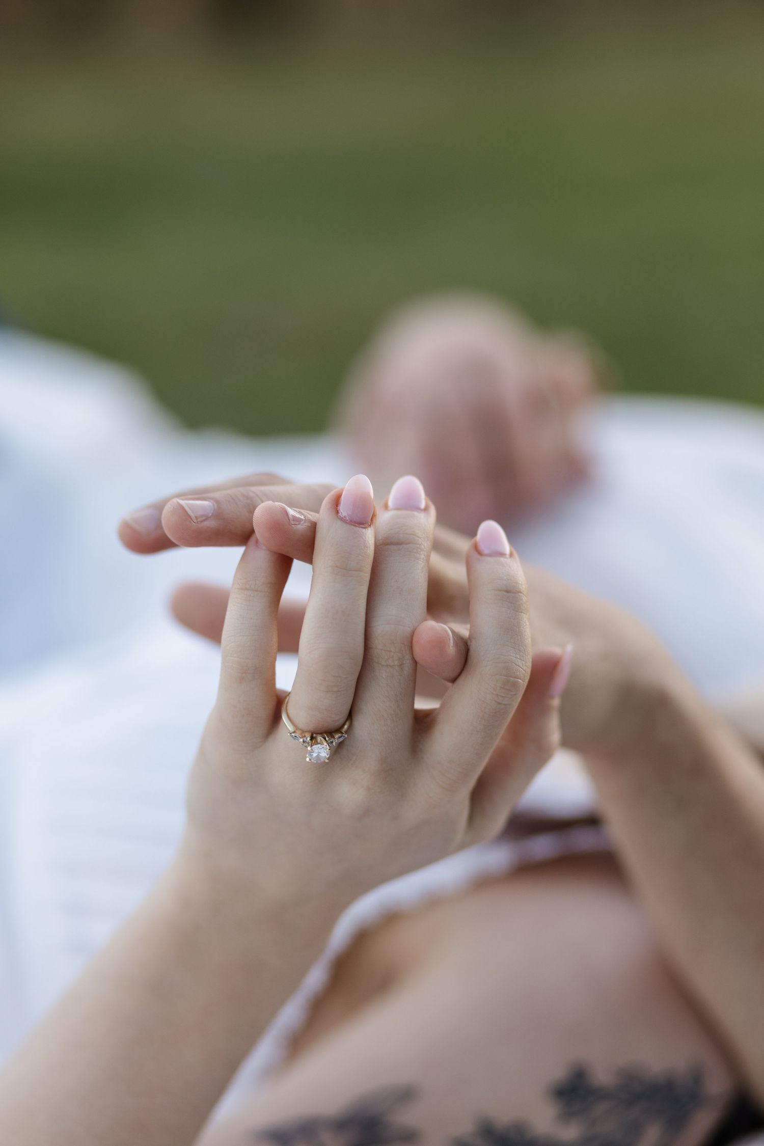 Close-up of hands with an engagement ring against a white background.