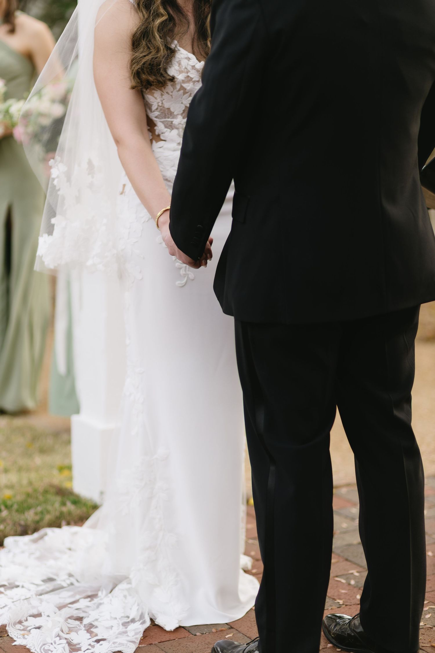 A close-up of wedding attire showing a white lace dress and black tuxedo.