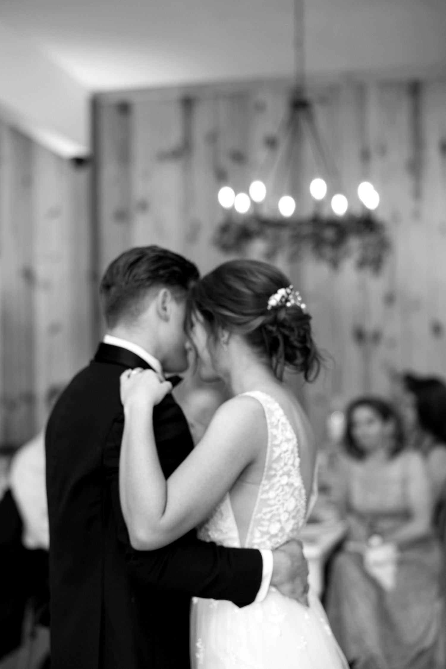 A romantic dance moment captured in black and white under a chandelier.