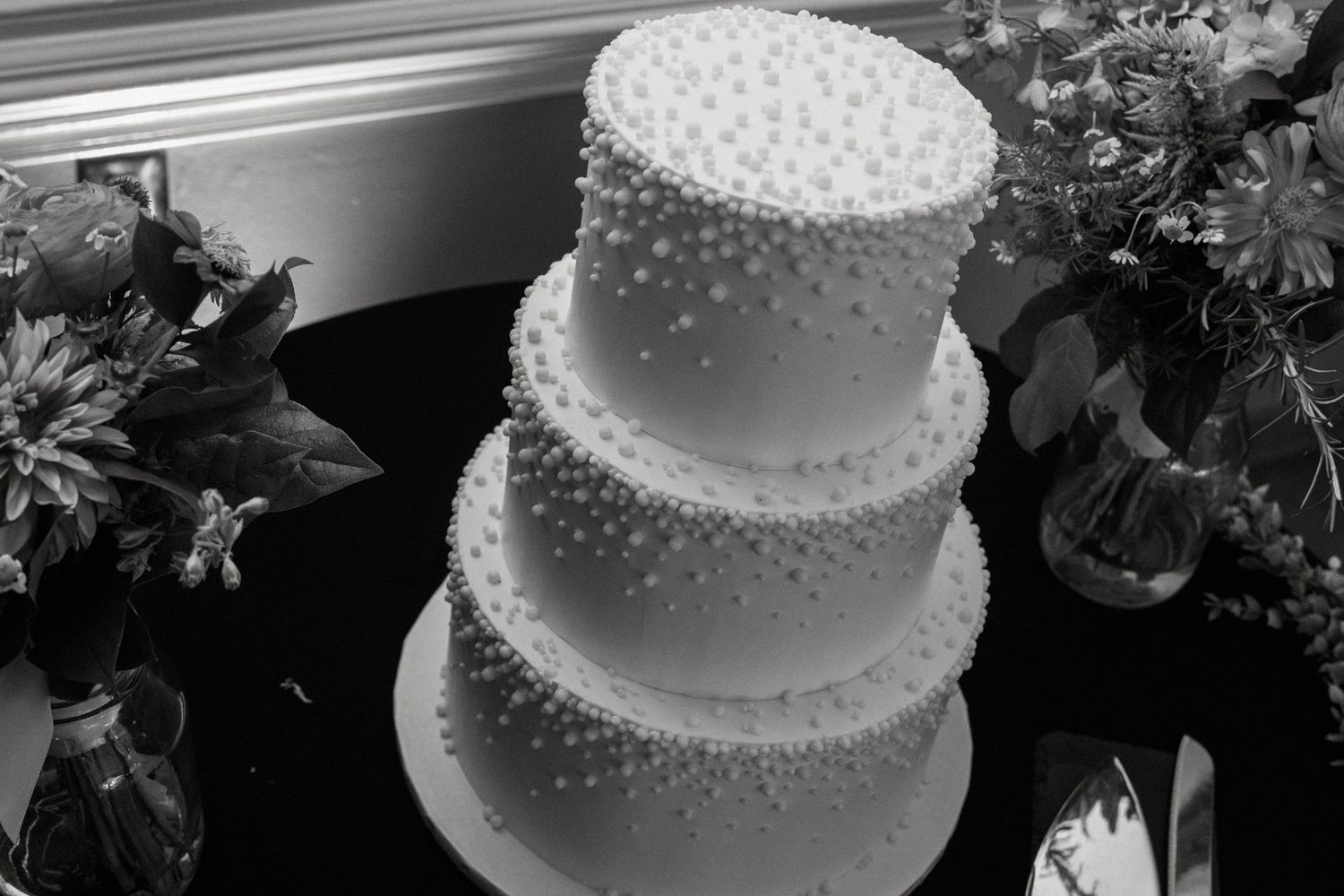 White tiered wedding cake decorated with delicate pearl-like dots in a classic elegant style.