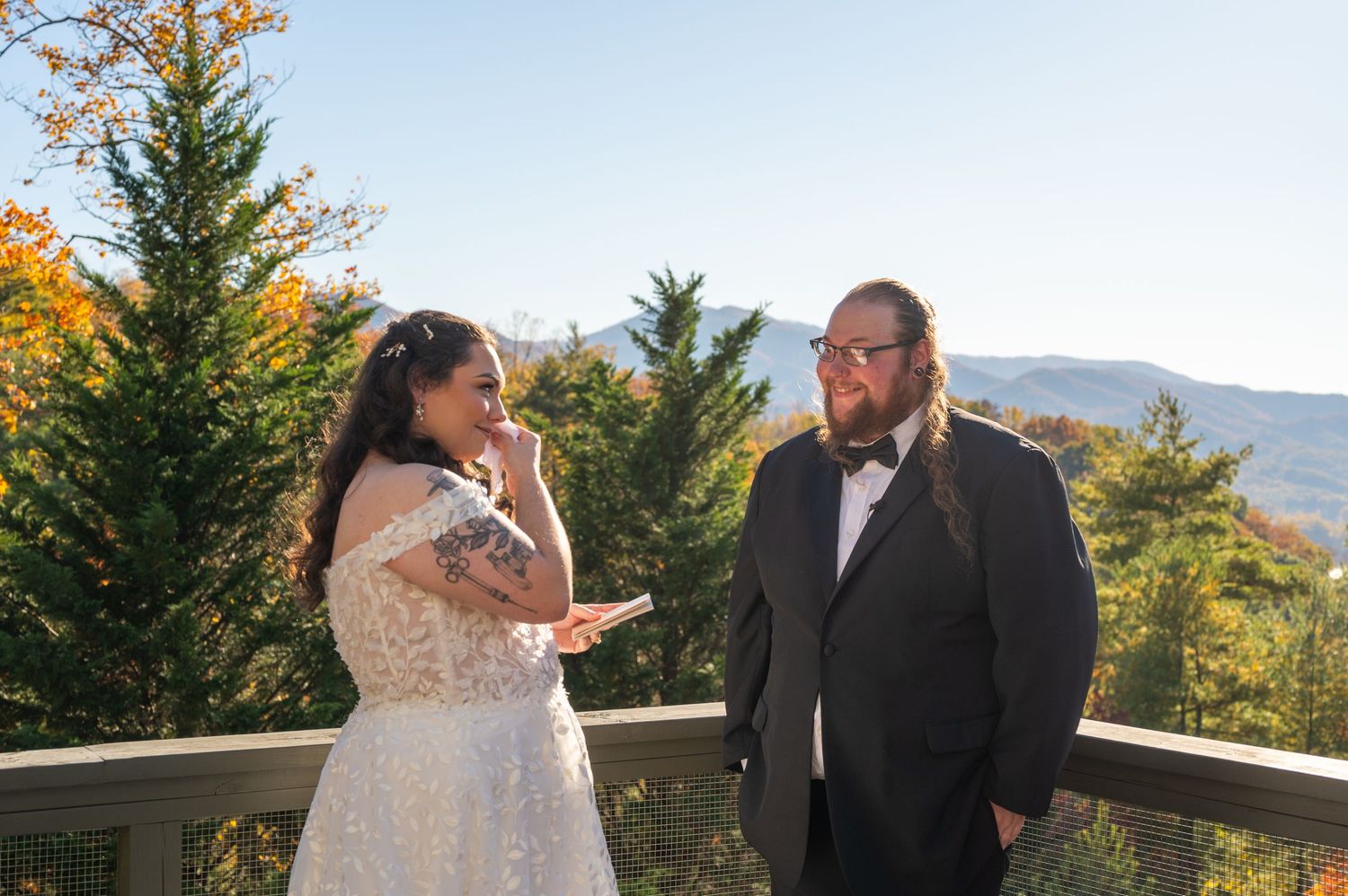 Couple sharing joyful moment during outdoor autumn mountain wedding ceremony.