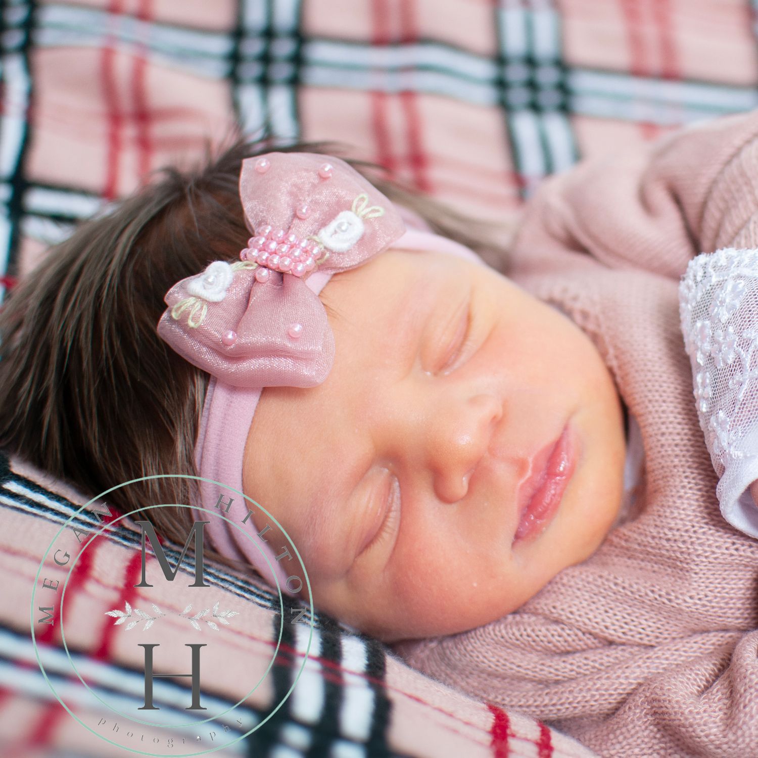 Baby girl sleeping on plaid pink blanket