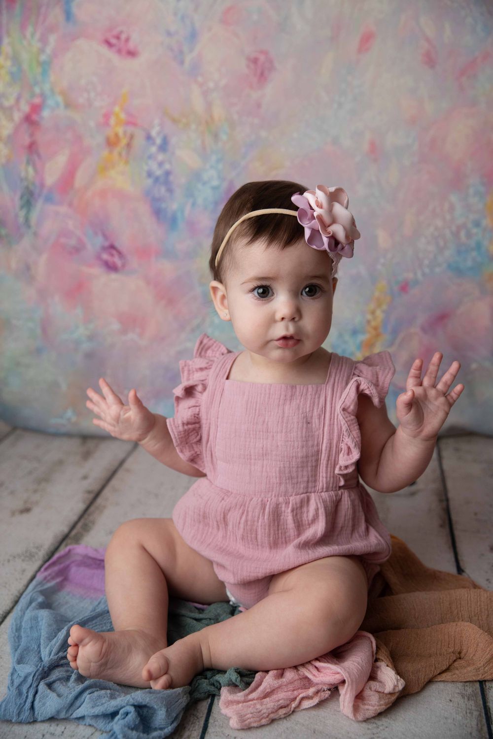 Baby girl in a pink outfit during milestone photography session in studio.