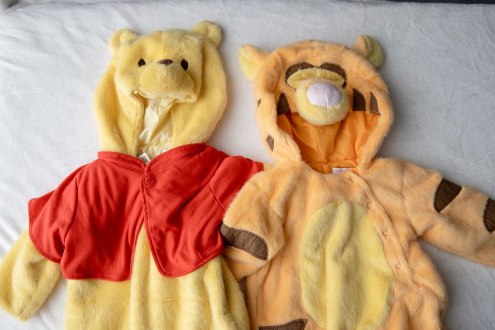 Two Disney baby costumes, Winnie the Pooh and Tigger, displayed side by side on white background.