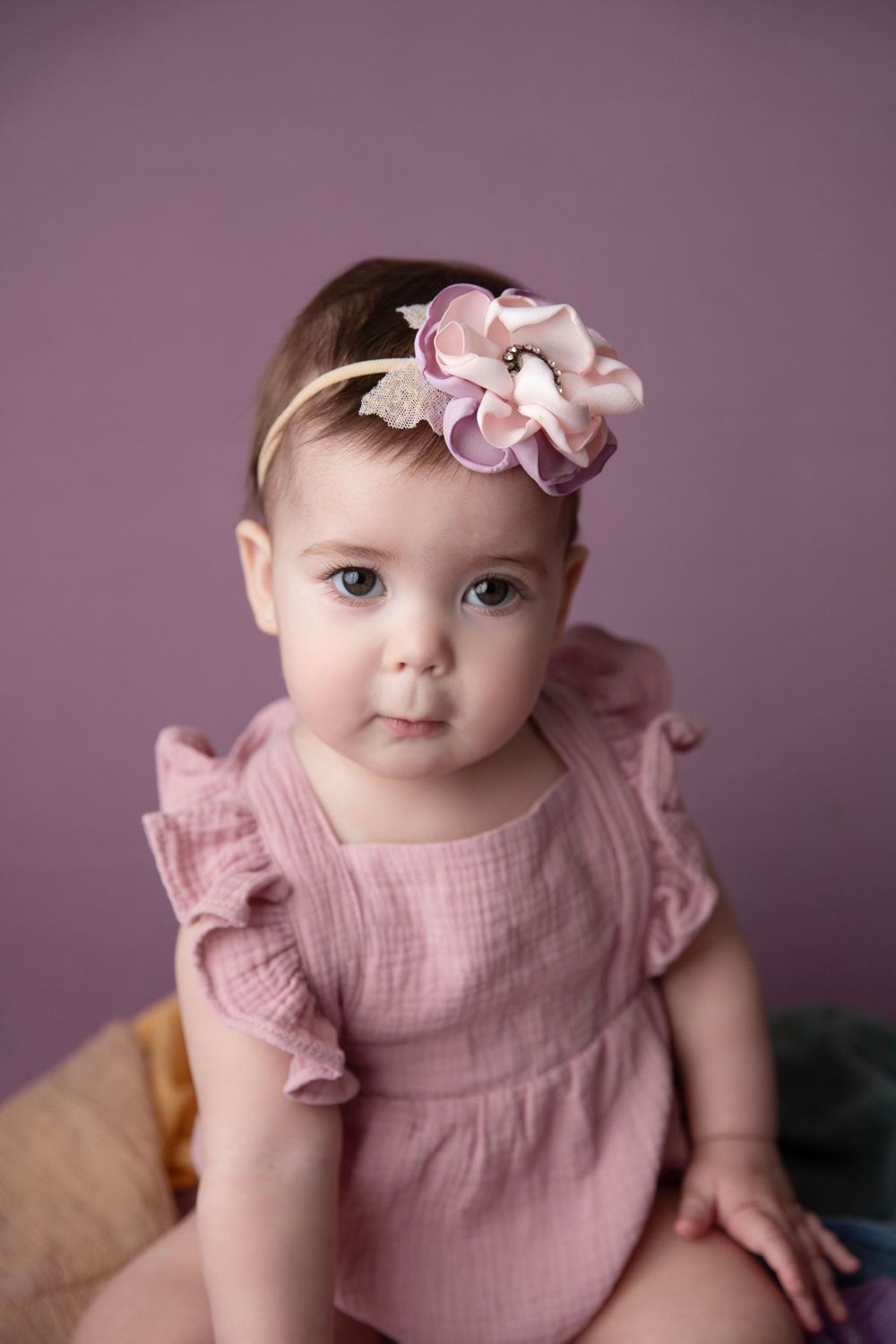 Baby girl in pink romper with floral headband during milestone photography session in Orange City Florida
