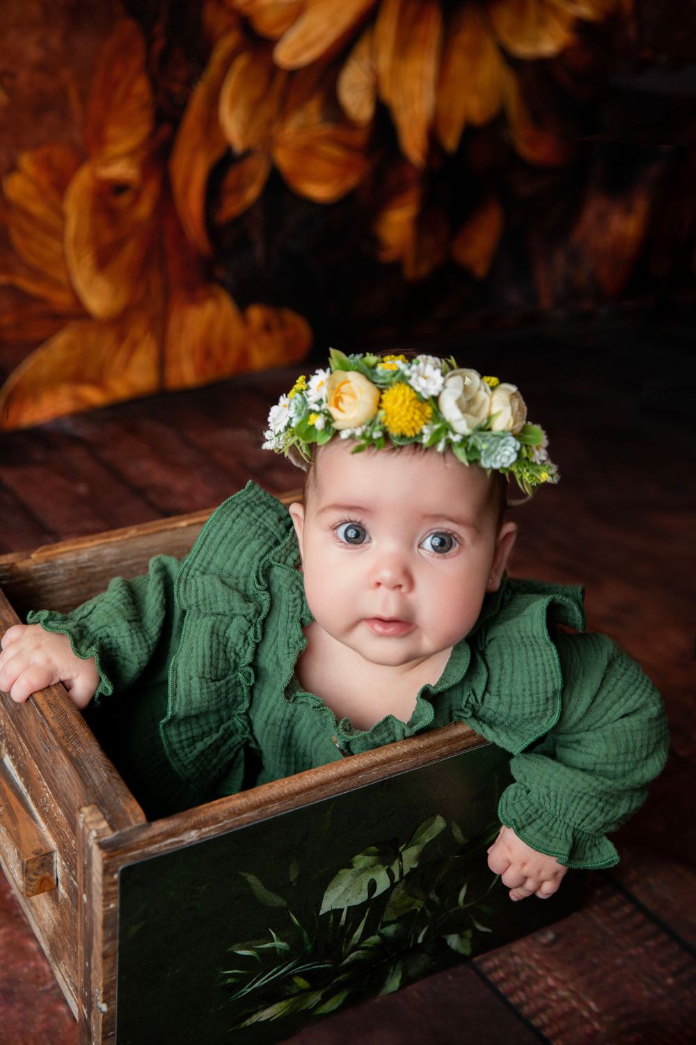 Baby in green outfit with floral crown during themed milestone photography session in Central Florida.