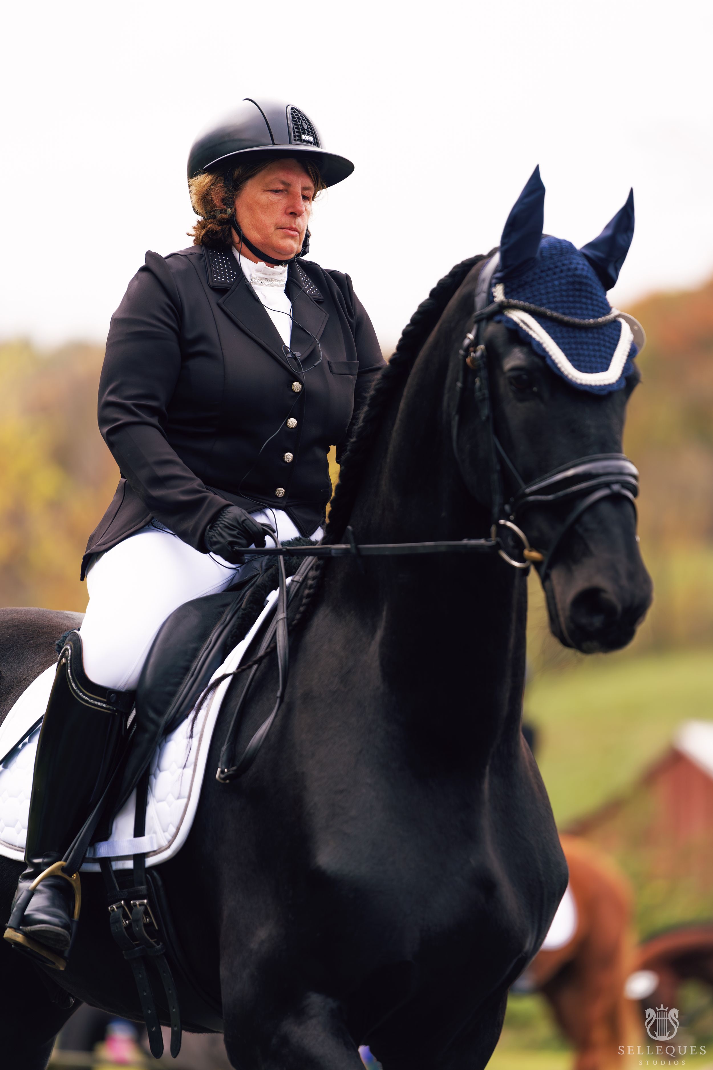 Rider in formal dressage attire aboard a beautiful black horse with decorative bridle.