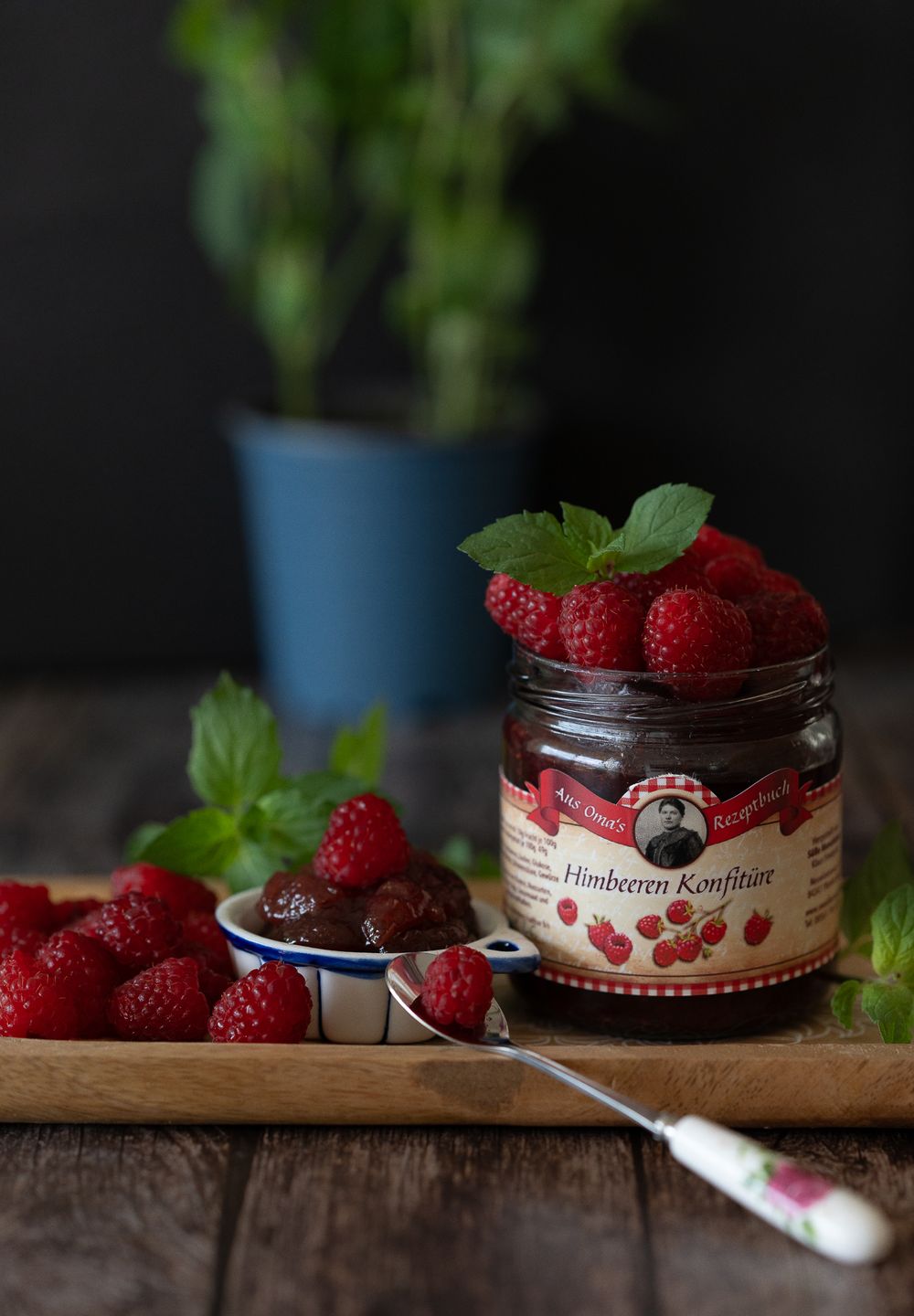 Foodfotografie. Fresh raspberries and jar of jam with mint leaves on wooden surface.