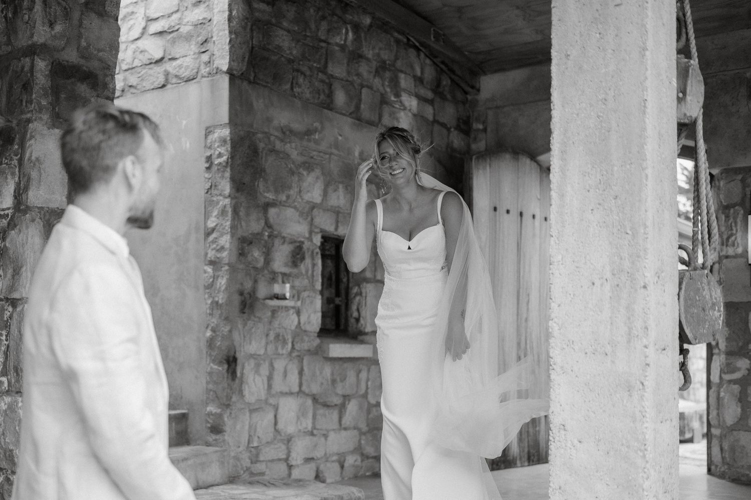 A romantic first look moment between newlyweds under stone architecture in black and white.
