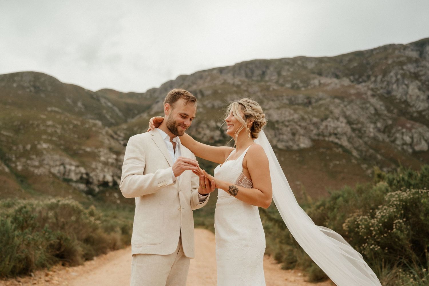 A couple sharing an intimate moment against a backdrop of rugged mountains during their wedding ceremony.